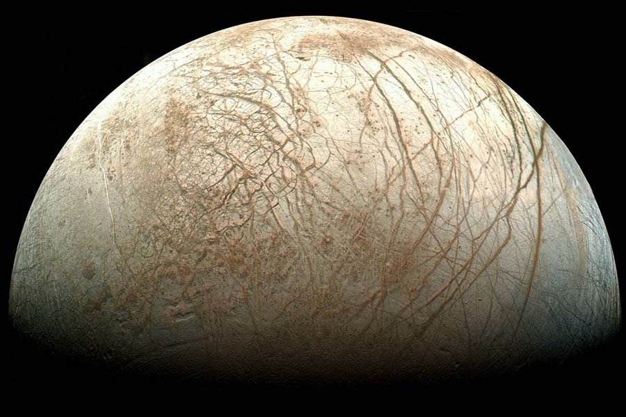 Der Mond Europa ist von oben zur Hälfte beleuchtet, über seiner hellen Oberfläche verlaufen braune lange Risse.