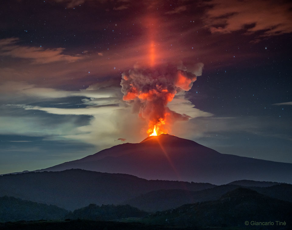 Eiskristalle über dem Ätna in Italien reflektieren das Licht der glühenden Magma bei einem Vulkanausbruch.