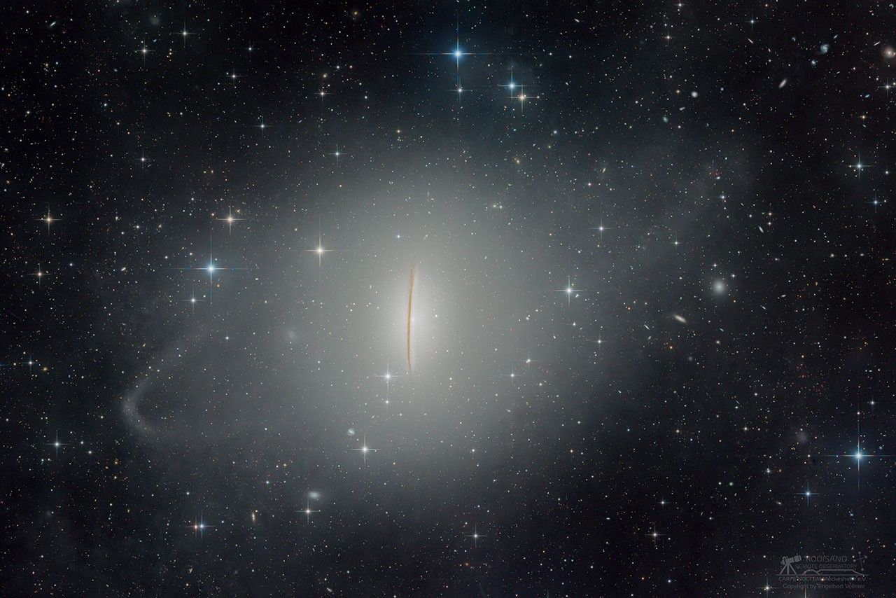 Die Sombrerogalaxie im Bild ist schwer erkennbar, weil so viele blasse Sternströme und der Halo um die Galaxie abgebildet wurden. Doch der markante Staubring am Rand der zentralen Scheibe ist klar in der Mitte erkennbar. Außen ist die Galaxie von Sternen und kleineren Galaxien umgeben.